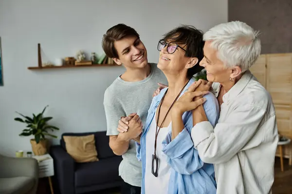 Un momento de amor como hijo comparte la risa y la alegría con sus padres lesbianas en casa. - foto de stock