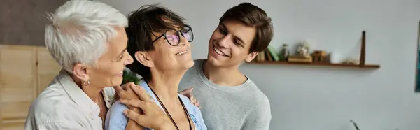 Lesbian parents and their adult son joyfully sharing laughter and closeness in a cozy living space. — Stock Photo
