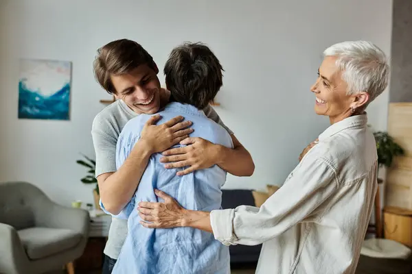 Lesbian parents and their adult son share a joyful embrace, celebrating love and family bonds. — Stock Photo
