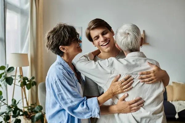 A joyful time is shared as a young man embraces his lesbian parents in a warm, inviting home. — Stock Photo