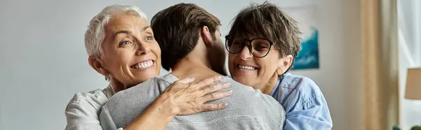 A warm moment shared as lesbian parents embrace their adult son, celebrating love and connection. — Stock Photo