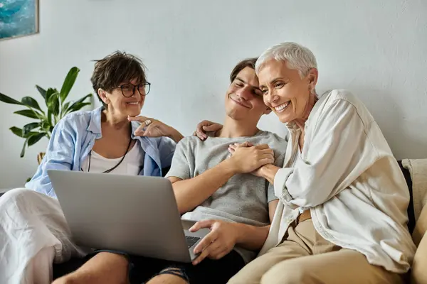 Lesbian parents and their adult son share laughter and joy while enjoying time together at home. — Stock Photo