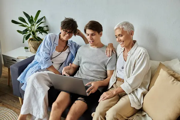 Lesbian parents and their adult son share laughter and joy while enjoying a laptop together. — Stock Photo