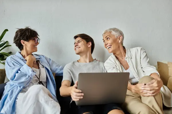 Lesbian parents enjoy a joyful afternoon with their adult son, sharing laughter and love in a cozy setting. — Stock Photo