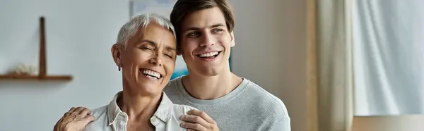 Una madre alegre y su hijo adulto comparten la risa y el calor en su acogedora sala de estar. — Stock Photo