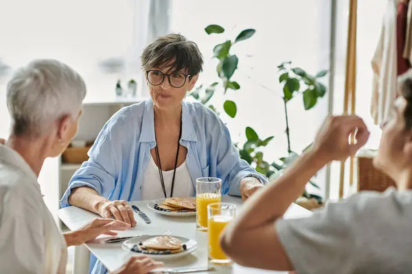 A joyful LGBTQ family shares a warm breakfast, filled with laughter and love, in their sunlit kitchen. — Stock Photo