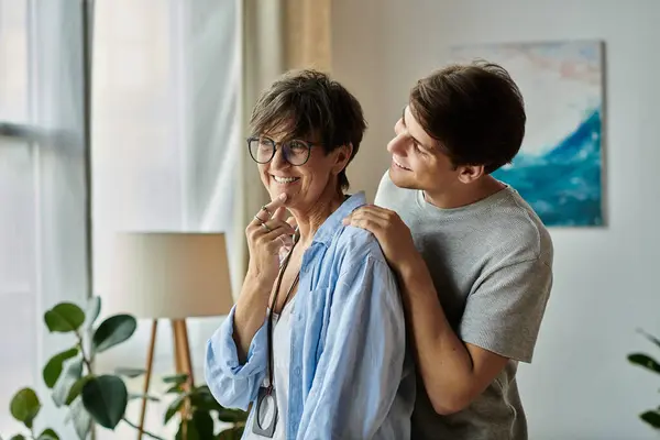 A cheerful mother and her adult son share laughter and warmth in their cozy, bright living space. — Stock Photo