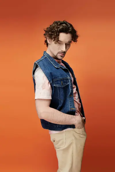 A stylish man showcases emotion in front of a bold orange background. — Stock Photo