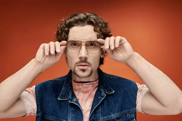 Un homme aux cheveux bouclés exprime ses émotions en ajustant ses lunettes. — Photo de stock