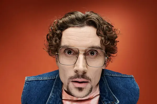 A handsome man with curly hair expresses deep emotion on a colorful backdrop. — Stock Photo