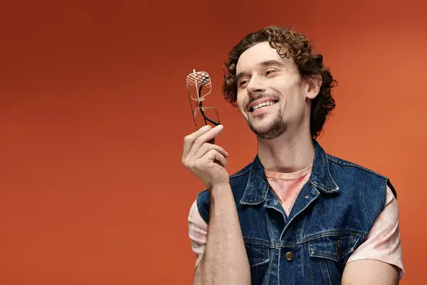 A charming man enjoys a moment, smiling and holding glasses against a bright background. — Stock Photo