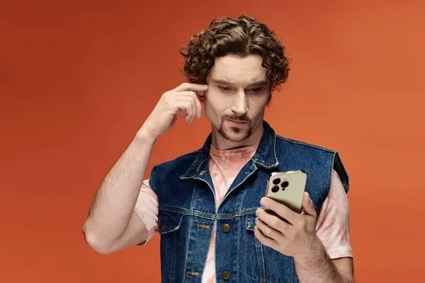 A handsome man appears thoughtful, engaging with his smartphone amid vibrant colors. — Stock Photo