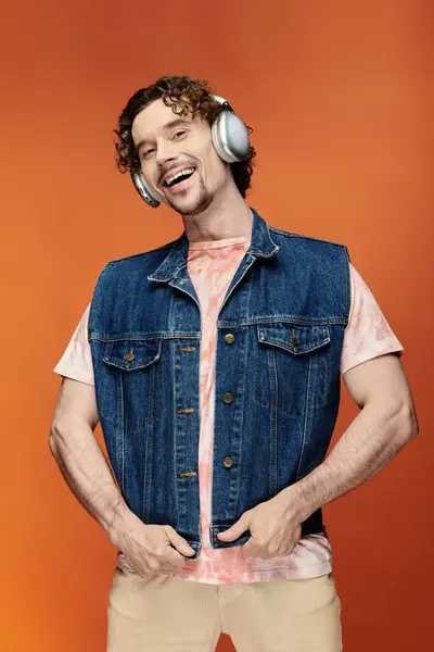A joyful man wearing headphones poses with confidence on a vibrant background. — Stock Photo