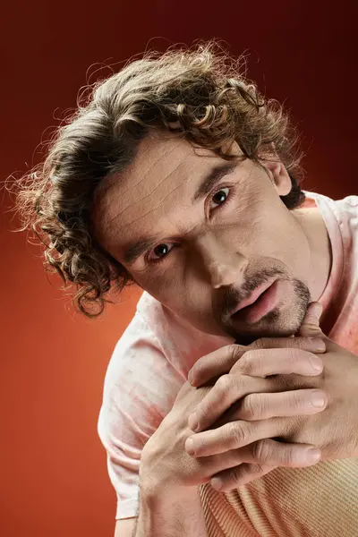 A handsome man displays deep emotion while posing with clasped hands. — Stock Photo
