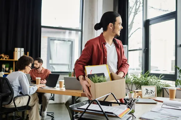 Team members working while one packing items while managing workplace transitions. — Stock Photo