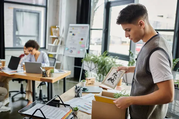 Man packing for a layoff, colleagues on backdrop. — Stock Photo