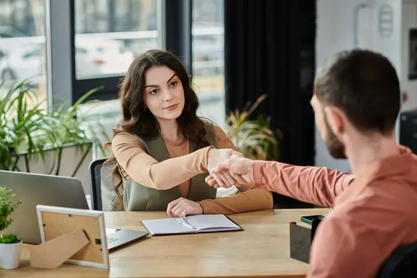 Dos profesionales participan en un apretón de manos en medio de una tensa conversación de despido. - foto de stock
