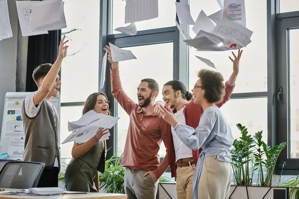 Group of colleagues joyfully releasing papers during a challenging moment. — Stock Photo