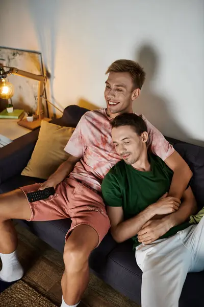 Two men cuddle on the couch, sharing a joyful moment in their living room. — Stock Photo