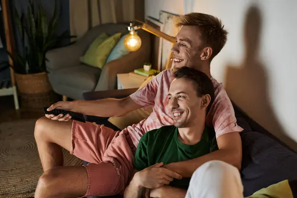 Two men enjoy a cozy afternoon on the couch, sharing smiles and warmth. — Stock Photo