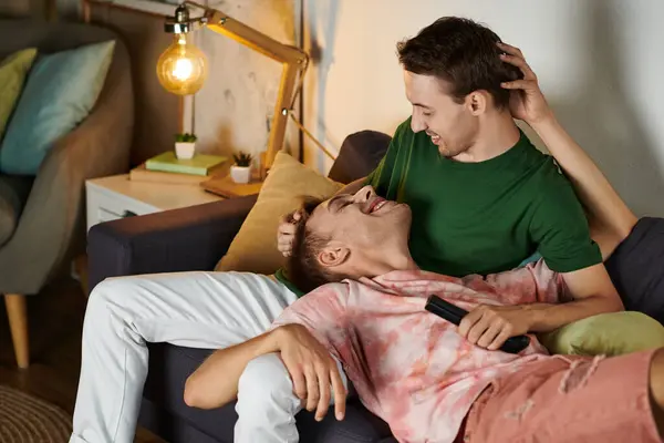 Two men enjoy laughter and affection while relaxing on their sofa. — Stock Photo
