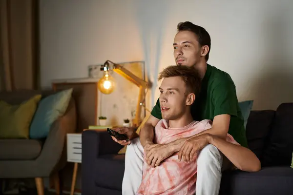 Two men relax at home, sharing a moment of warmth while watching TV. — Stock Photo