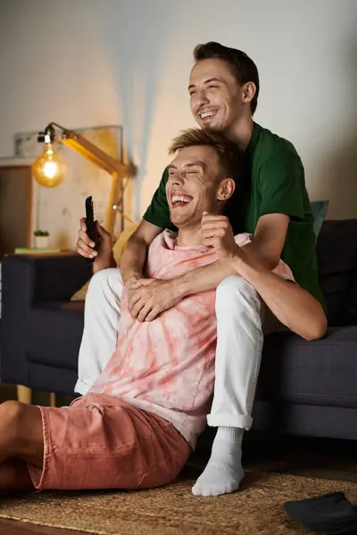 Two joyful men share laughter and love while relaxing on their couch. — Stock Photo