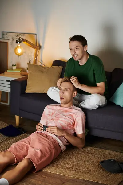 Two men share laughter and gaming fun together on their living room floor. — Stock Photo