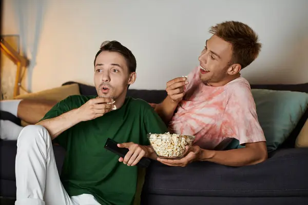 Aimer couple partage pop-corn tout en regardant un film et rire à la maison. — Photo de stock