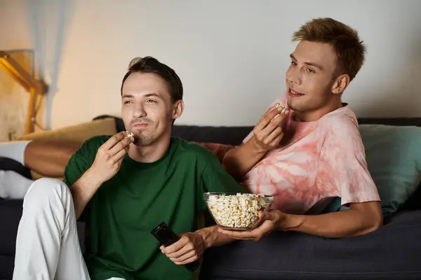 A joyful couple enjoys popcorn while relaxing together on the couch. — Stock Photo