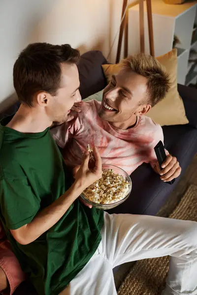 Two men share a joyful moment while cuddling on the couch. — Stock Photo