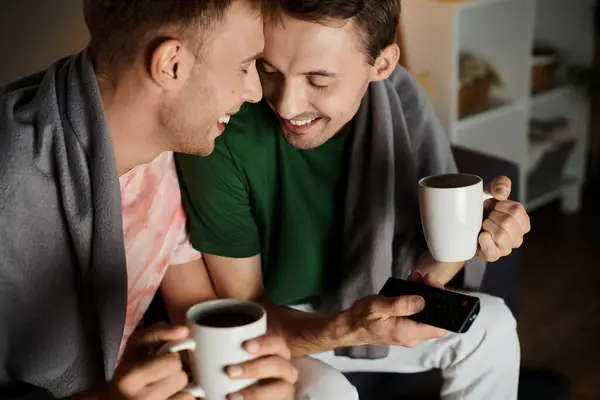 Two men enjoy a cozy moment, sharing smiles and beverages together. — Stock Photo