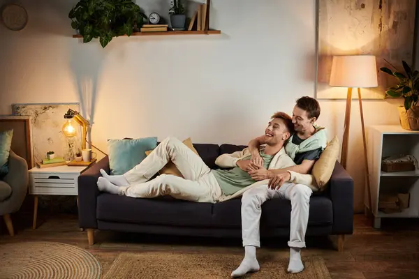 Two men enjoy a tender moment together on a comfortable sofa in their home. — Stock Photo