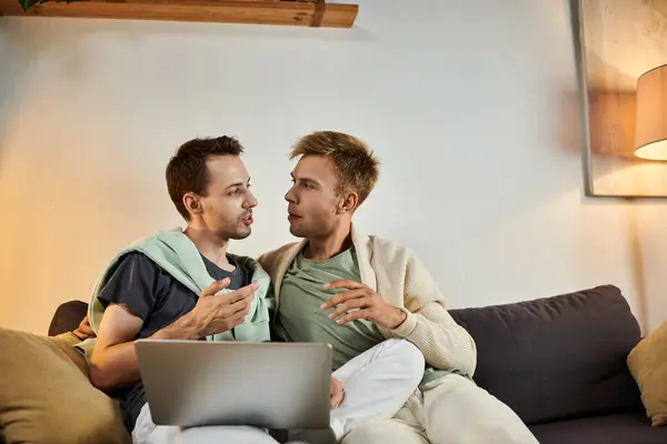 Due uomini condividono un momento caldo mentre chattano sul divano. — Foto stock