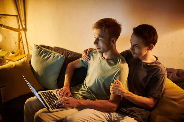 Two men share a tender moment while collaborating at home on a laptop. — Stock Photo
