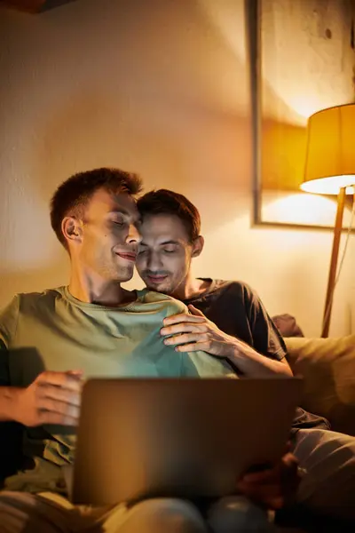 Un couple aimant se détend à la maison, partageant un moment chaleureux tout en utilisant un ordinateur portable. — Photo de stock