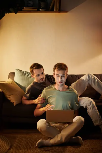 Two men share a relaxed moment at home while using their laptop. — Stock Photo