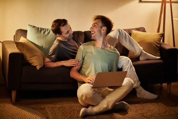 Due uomini condividono risate e connessione mentre si rilassano sul divano. — Foto stock