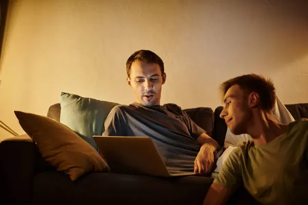 Two men share a warm moment while looking at a laptop at home. — Stock Photo
