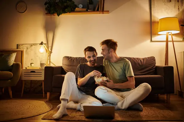 A loving couple shares popcorn while laughing on a cozy evening. — Stock Photo