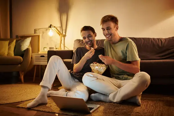A loving couple relaxes on the floor, sharing popcorn while watching something enjoyable. — Stock Photo