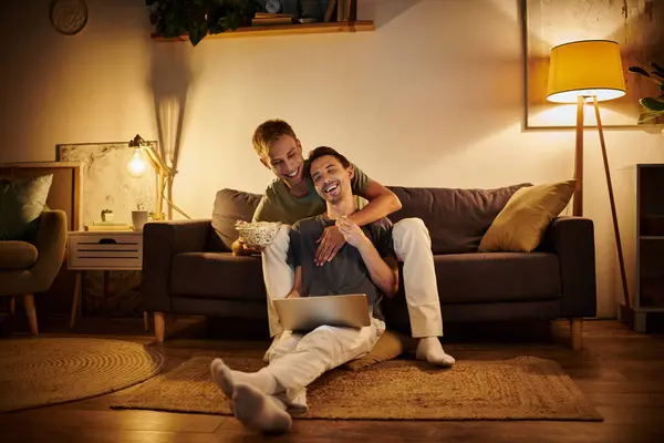 Two men share a joyful moment together, enjoying each other in their cozy home. — Stock Photo