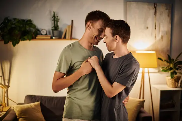 Dois homens abraçam-se alegremente em seu espaço de vida íntimo juntos. — Fotografia de Stock