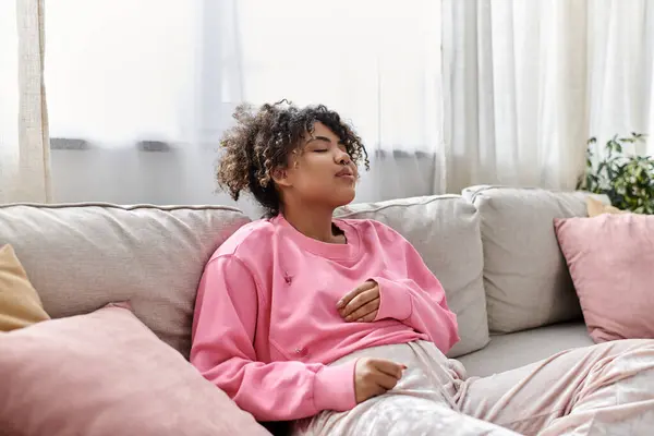 A young woman relaxes thoughtfully on a comfortable couch, embracing tranquility. — Stock Photo