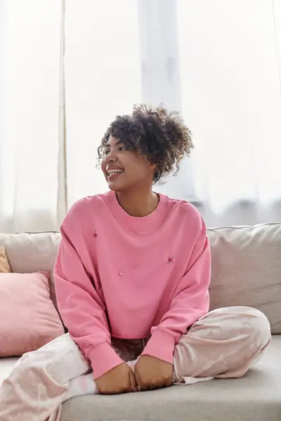 Mulher sorridente vestida casualmente desfruta de um dia tranquilo em sua casa ensolarada. — Fotografia de Stock