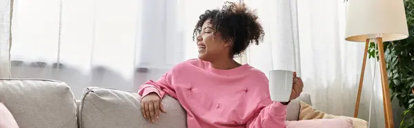 A young woman relaxes at home with a comforting beverage in hand. — Stock Photo