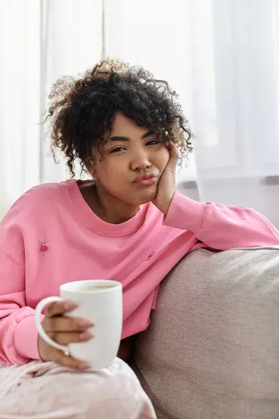 A young woman enjoys a warm drink while lounging comfortably at home. — Stock Photo