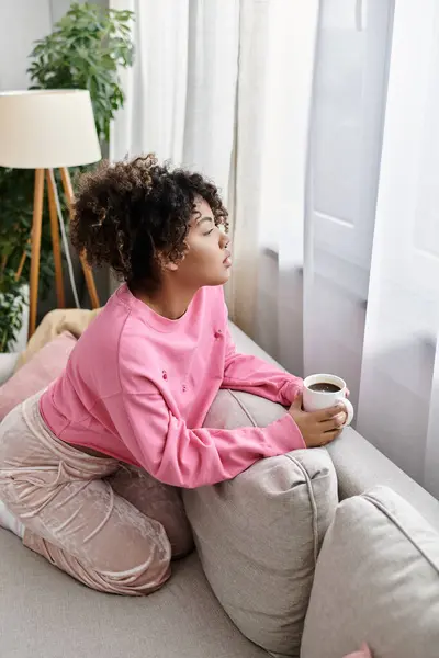 A young woman enjoys a quiet moment, sipping coffee by the window. — Stock Photo