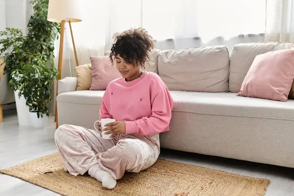 Une jeune femme se détend avec une tasse de thé dans un salon confortable. — Photo de stock