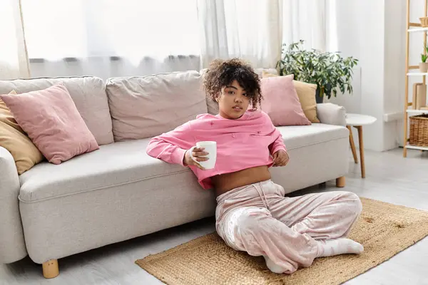 Uma jovem mulher desfruta de um momento de paz enquanto bebe uma bebida em casa. — Fotografia de Stock